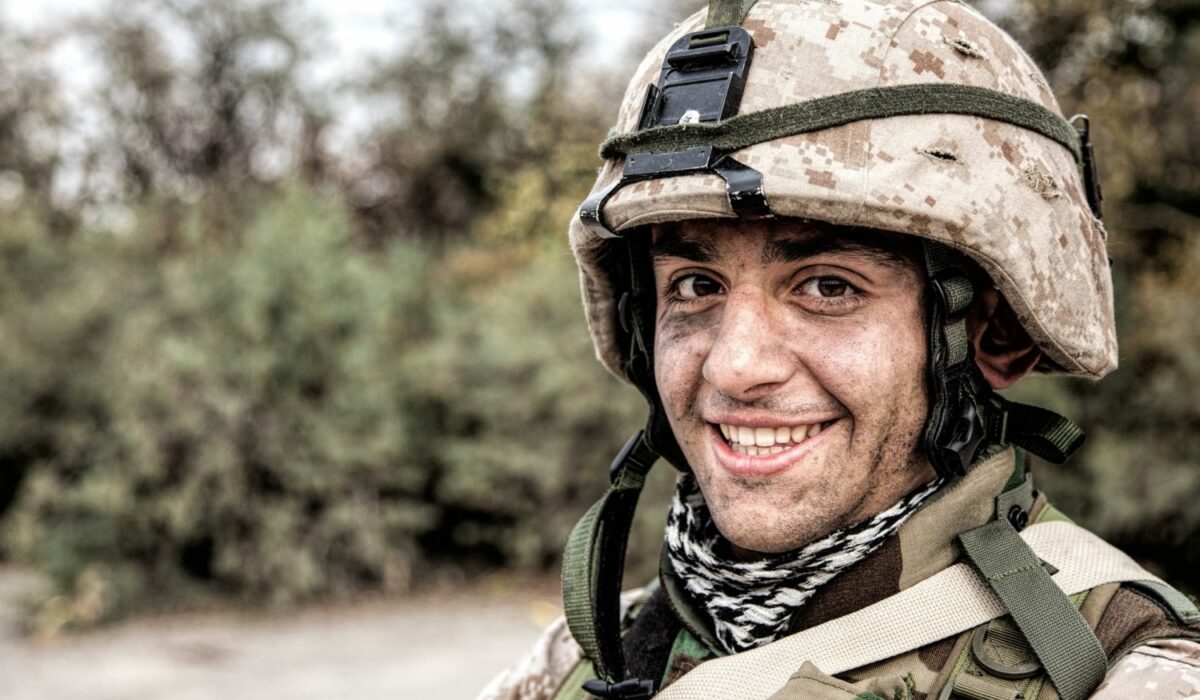 Portrait of smiling army soldier in ragged helmet